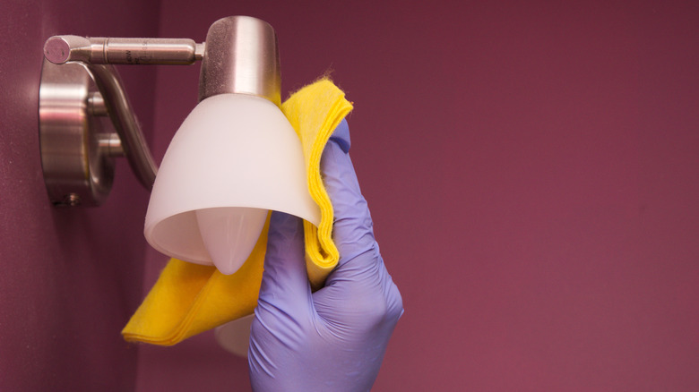 Person cleaning glass lampshade