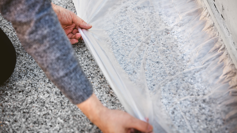 Hangs installing masking film over carpet