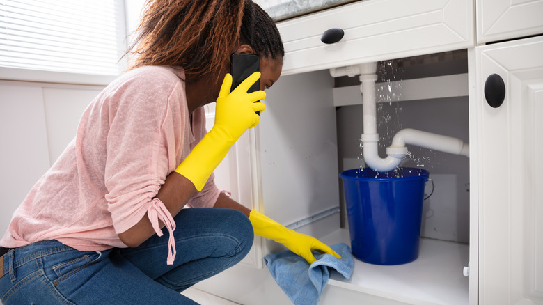 woman calling plumber for leaking pipe