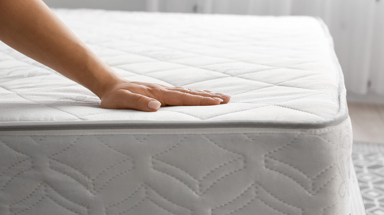 hand stroking a large mattress  