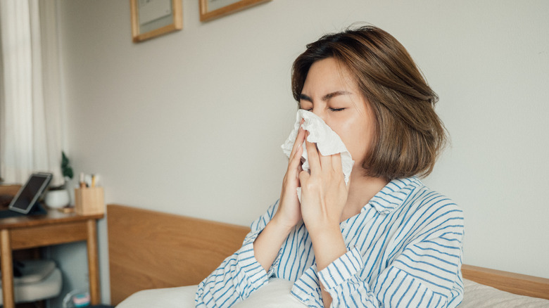 Woman blowing nose in bed