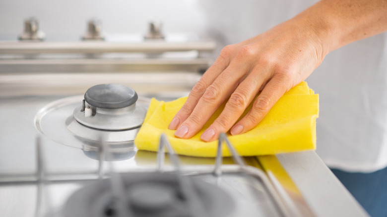 Person wiping stove with cloth