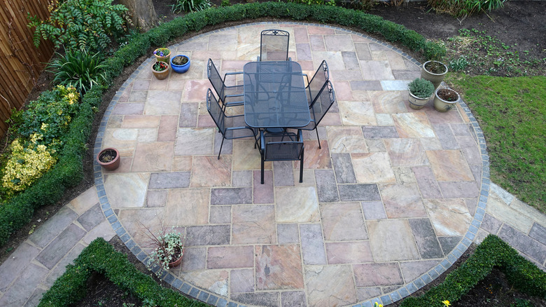 Circular garden patio with a table, chairs, and potted plants