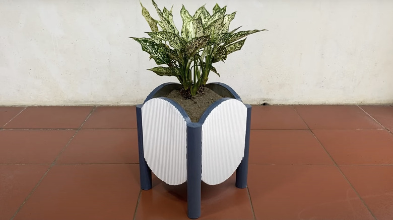 A cement planter with a fluted surface painted blue and white