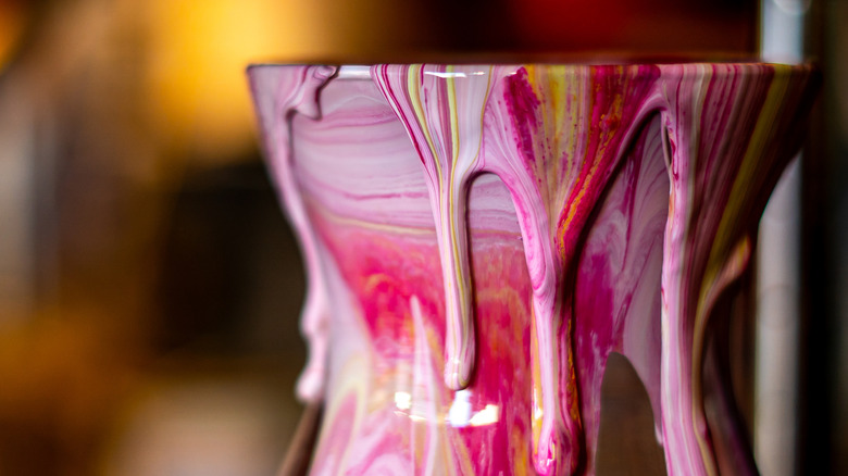 Marbled pink and gold paint dripping from vase