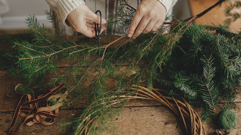 woman making holiday wreath with evergreens