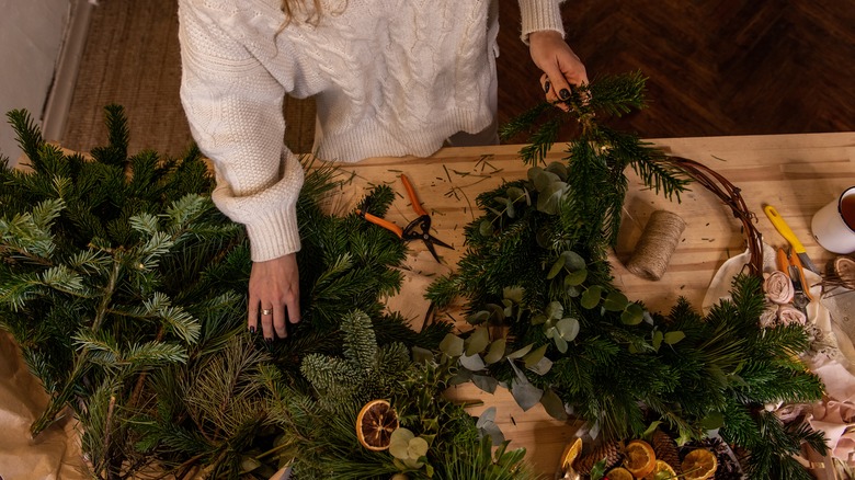 woman gathering materials to make holiday wreath