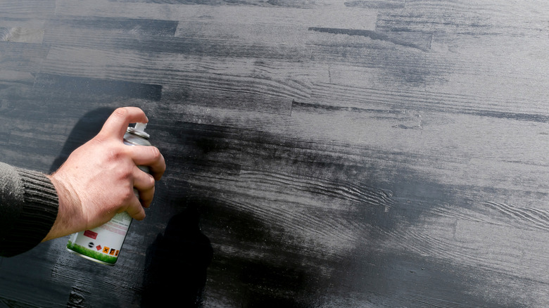 Person using metallic spray paint on a wooden table