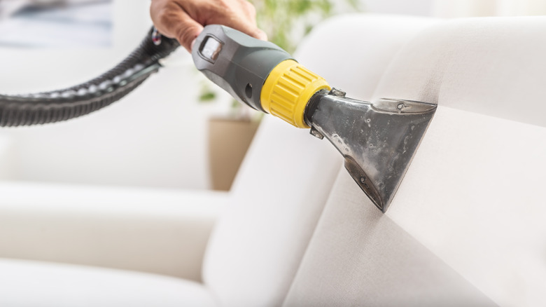 person steam cleaning sofa