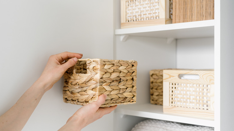 person shelving bamboo storage bins