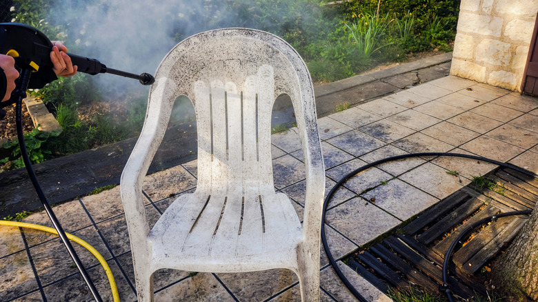 Person pressure washing dirty chair