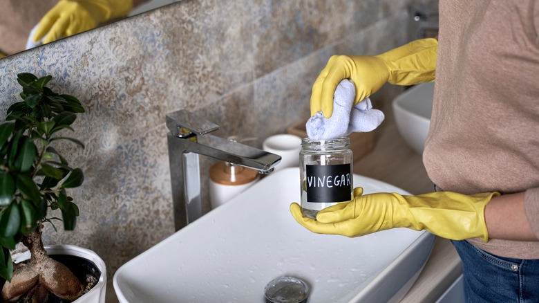 person cleaning bathroom with vinegar