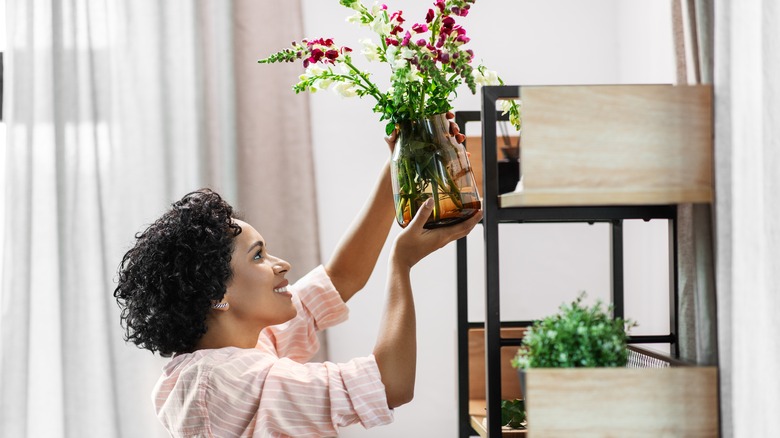 woman putting plant on shelf