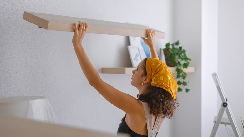 Woman hanging a shelf on a wall