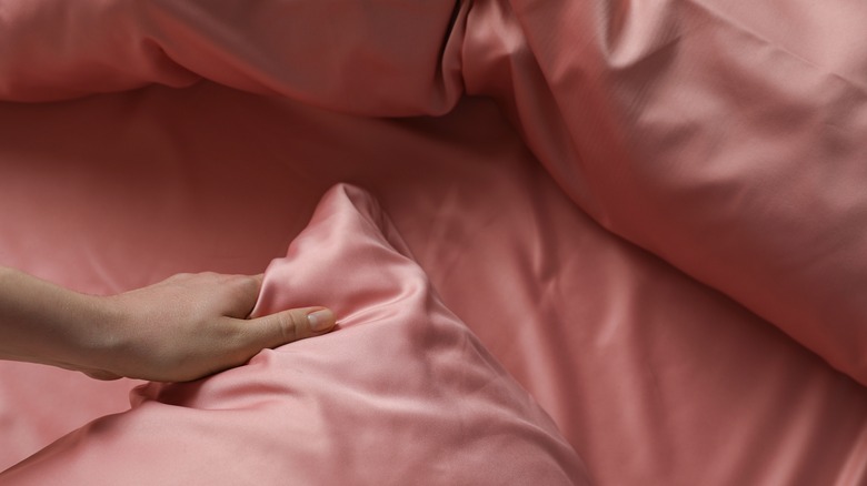 Pink silk sheets on bed