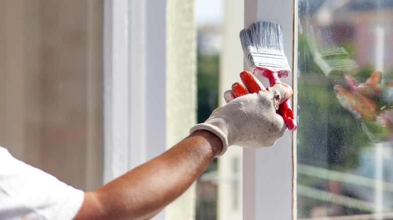 person painting window frame white