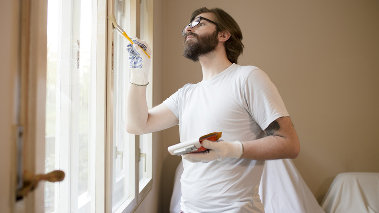 man painting window frame white