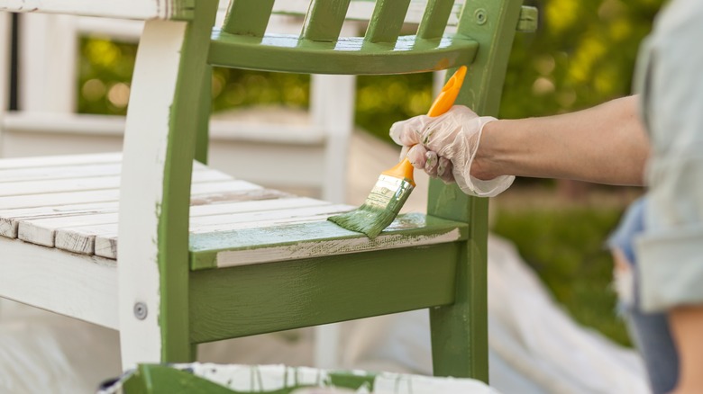 Person painting chair green