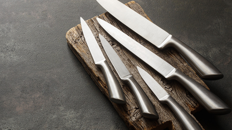 A set of kitchen knives rest on a cutting board.