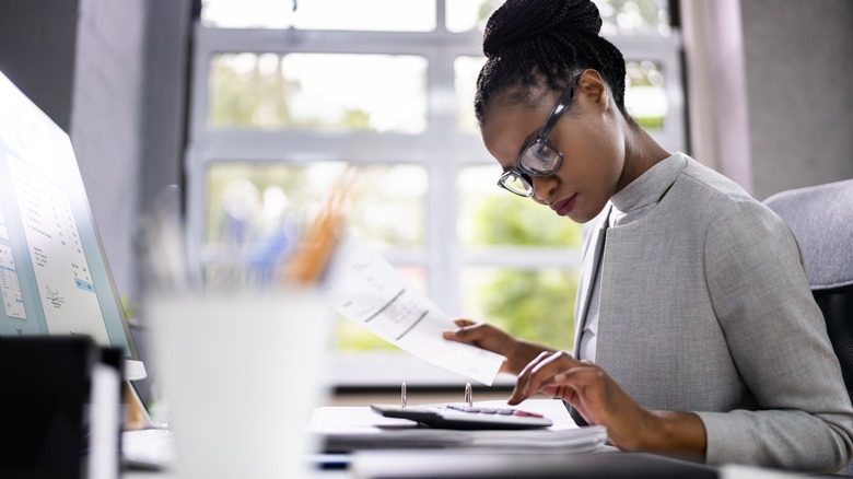 woman typing on calculator