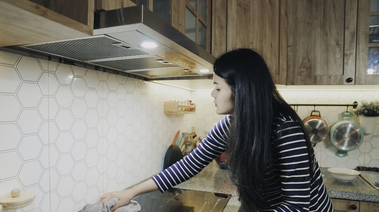 Woman standing under range hood 