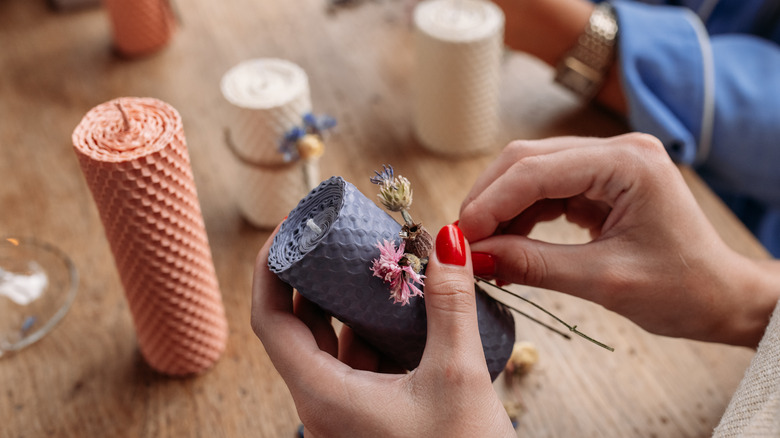 woman putting flowers on candle