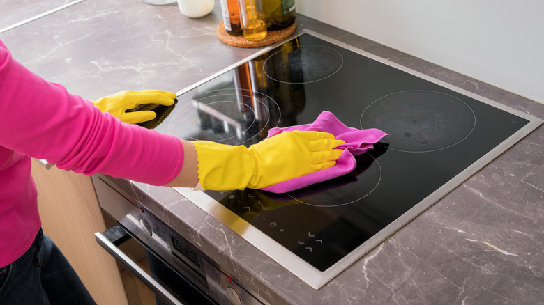 Gloved hand cleaning glass stovetop