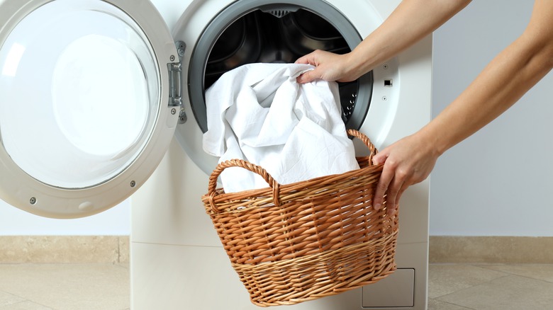 Person loading sheets into a washing machine