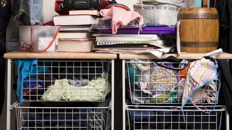 Disorganized clutter piled in and on top of wire storage drawers