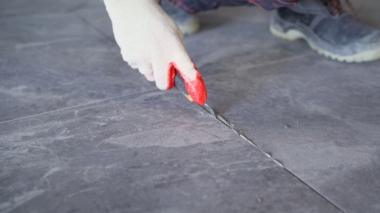 hand removing tile grout