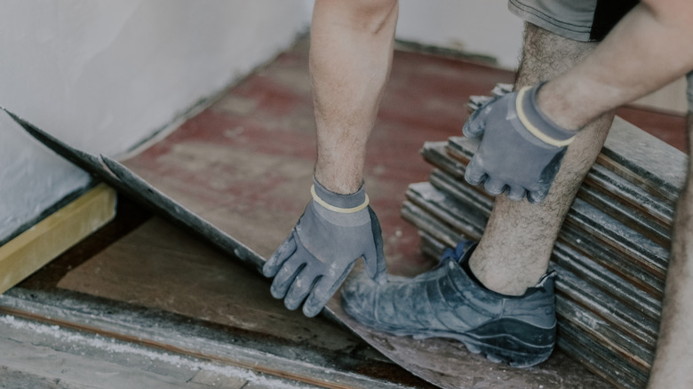 A man removing a dirty, old linoleum floor