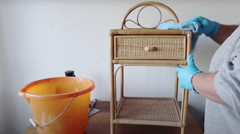 person cleaning wicker side table