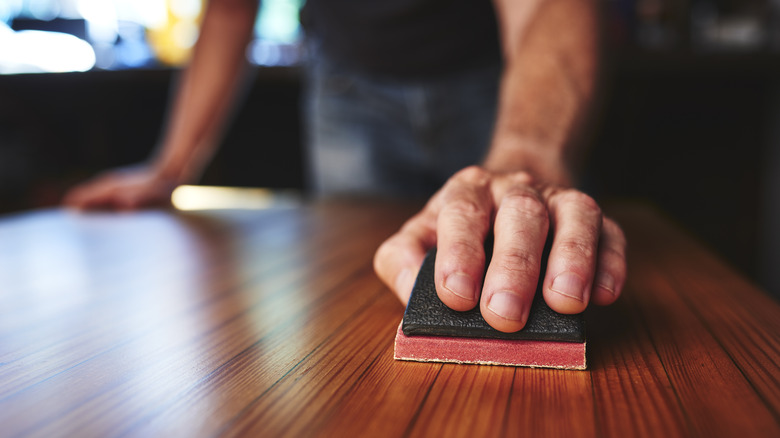 Person sanding wooden table