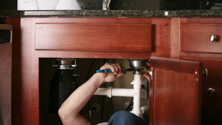 Plumber fixing sink in a home kitchen.