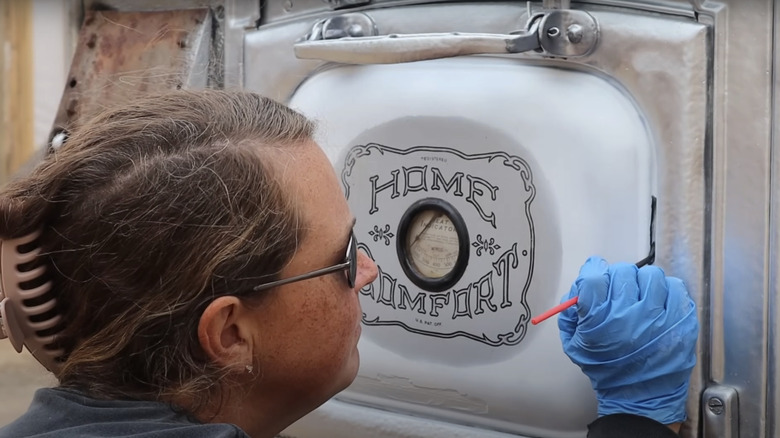 Woman painting enamel stove panel