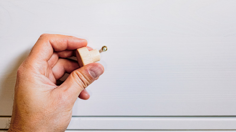 A person replaces drawer hardware