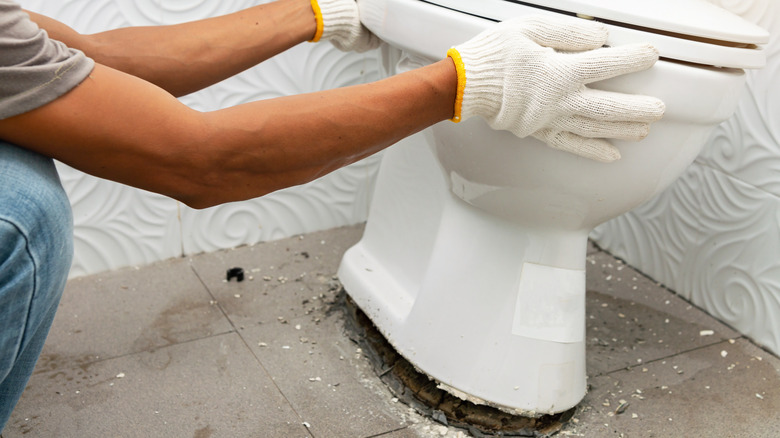 person pulls toilet loose from floor