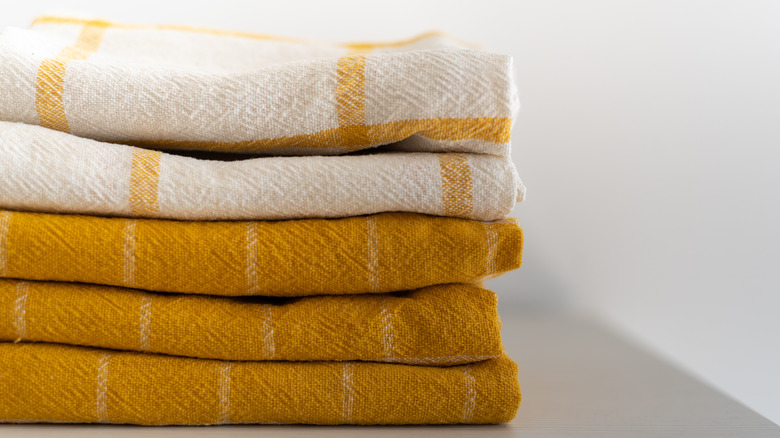 Gold and white kitchen towels stacked against white background