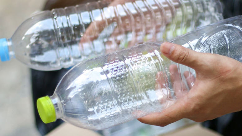 Someone holding empty plastic bottles