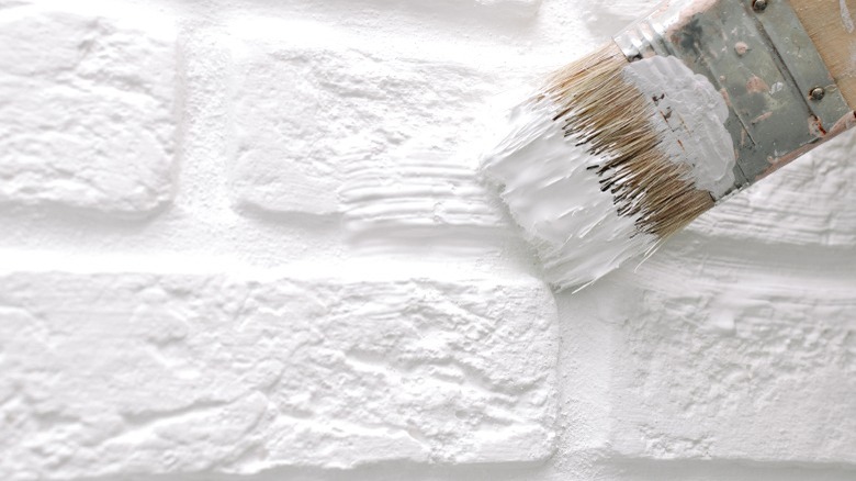 paintbrush painting white brick wall