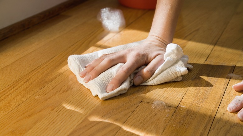 Person wiping hardwood floor surface