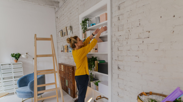 A woman arranging built-in closet shelves