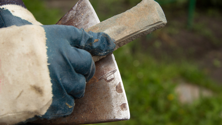 Person sharpening an axe with a file