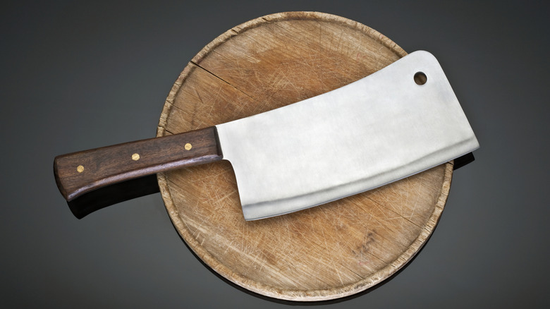 A cleaver rests on a wooden plate