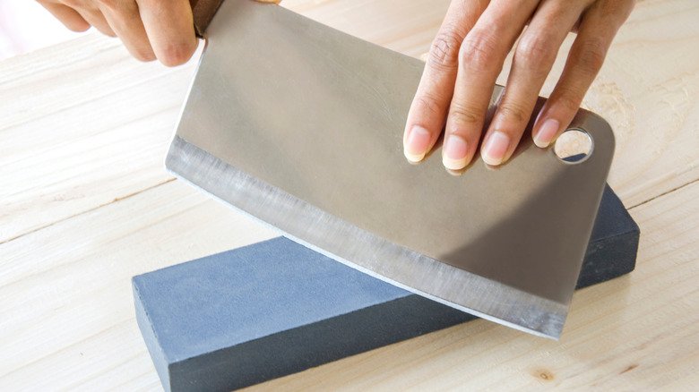 A person is sharpening a cleaver using a whetstone