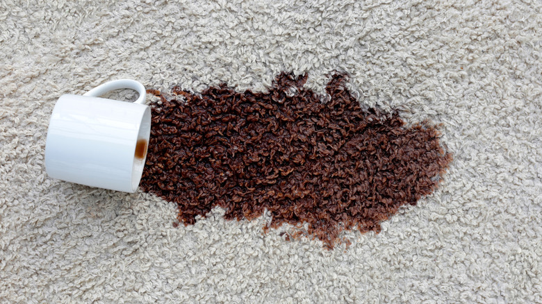 Mug of coffee spilled over on a white rug