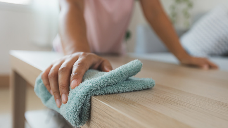 woman dusting furniture in home