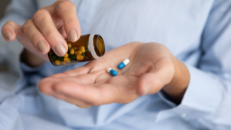 woman putting pills into hand