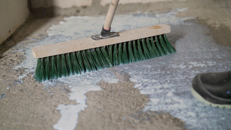 Soft brush with green bristles cleaning concrete floor