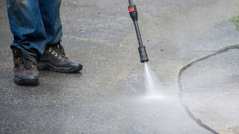 Someone power washing a concrete surface